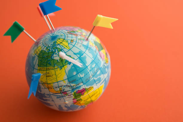 istock Color flag pins marks on earth globe with orange color background. 1617848046