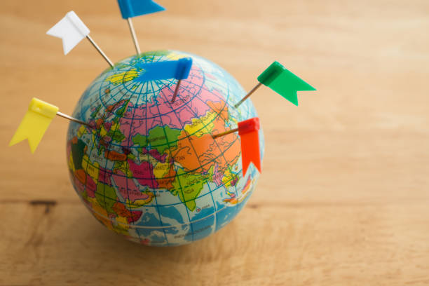 istock Color flag pins marks on earth globe with wooden table background. 1617848048
