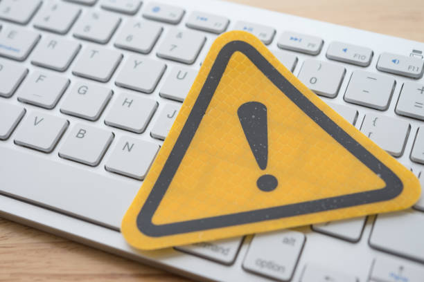 istock Yellow alert sign on white keyboard on wooden table background. 1617849382