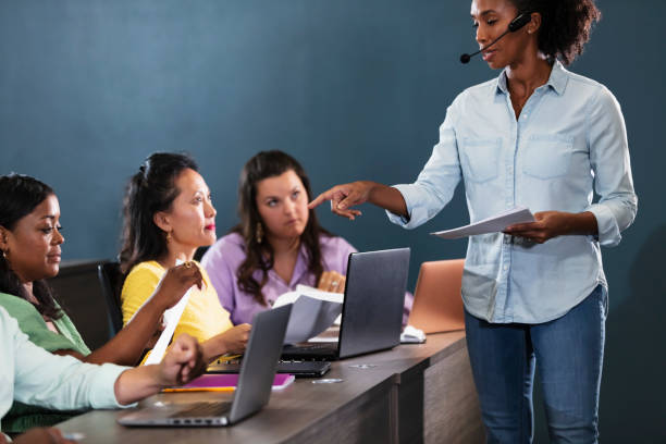 instructor talking to student in training class - mature student learning training computer imagens e fotografias de stock