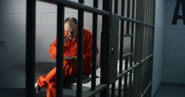 istock Elderly prisoner eats food sitting in prison cell in jail 1617858129
