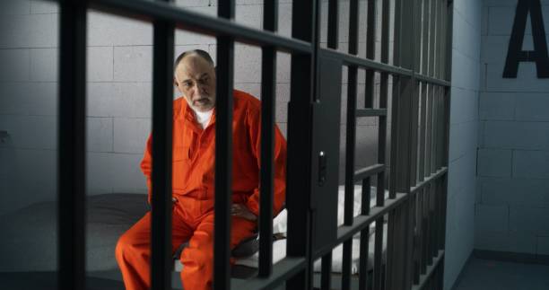 istock Criminal in orange uniform sits on prison bed 1617860744