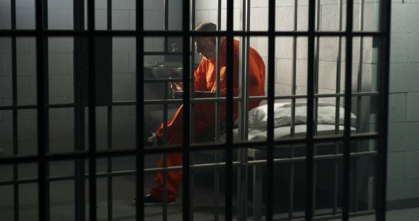 istock Elderly prisoner sits in prison cell in jail, eats food 1617863857