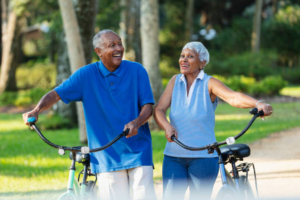istock Senior African American couple walk with bikes, laughing 1617864392