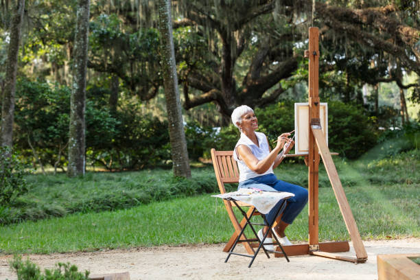 Senior African-American woman painting on canvas in park