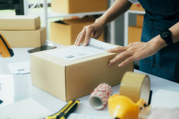 istock Young business owner putting shipping label on parcel. 1617889391