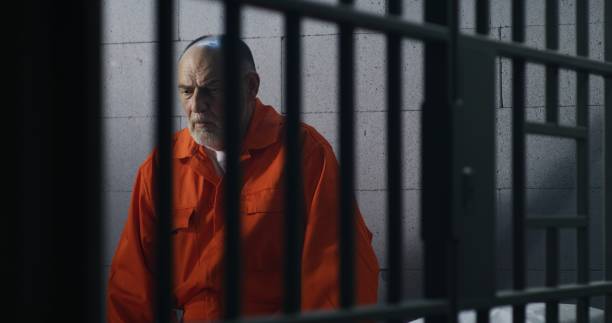 istock Criminal in orange uniform sits on prison bed 1617899308