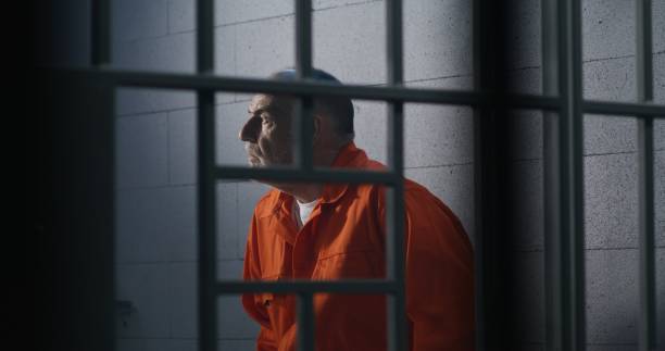 istock Criminal in orange uniform sits on prison bed 1617900377