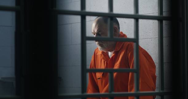 istock Criminal in orange uniform sits on prison bed 1617900922