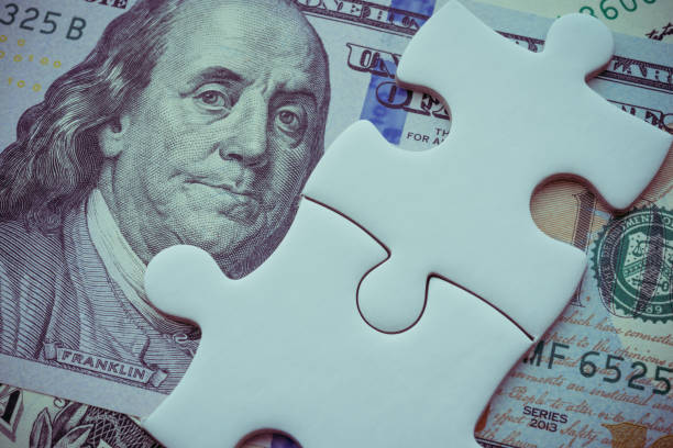 istock Benjamin Franklin president on US dollar banknote under unfinished white jigsaw puzzle. 1617927813