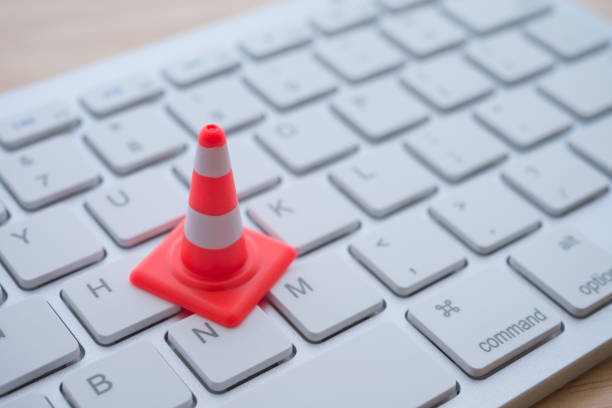 istock Close up single orange white traffic warning cone or pylon on keyboard computer background with copy space. 1617930143