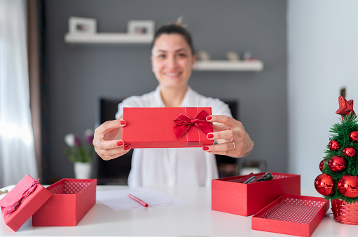 Woman Holding Christmas Gift Box Towards Camera