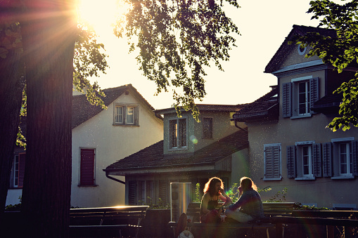 A lovely scene of two friends chatting on a bench at Lindenhof Hill (in Zurich, Switzerland) at sunset.