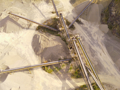 Industrial Extraction and Manufacturing. Aerial view of a gravel pit and conveyor belts for stone distribution. Active mining facility located on Mount Pangradinan. Cikancung, Bandung - Indonesia.