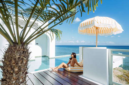 Beautiful tropical landscape with chairs, sand, ocean view with horizon, sunny sky, tranquility and relaxation.