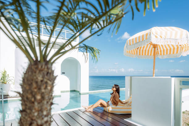 istock Beautiful Indonesian Relaxing Under Yellow Stripped Umbrella At the Infinity Pool Side 1618011088