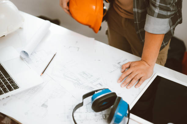 istock Architecture engineer working with blueprints and laptop in office. Inspection in workplace for architectural plan. Construction project. Adviser construction site engineer. 1618014192