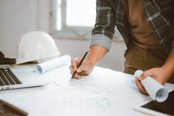 istock Architecture engineer working with blueprints and laptop in office. Inspection in workplace for architectural plan. Construction project. Adviser construction site engineer. 1618014732