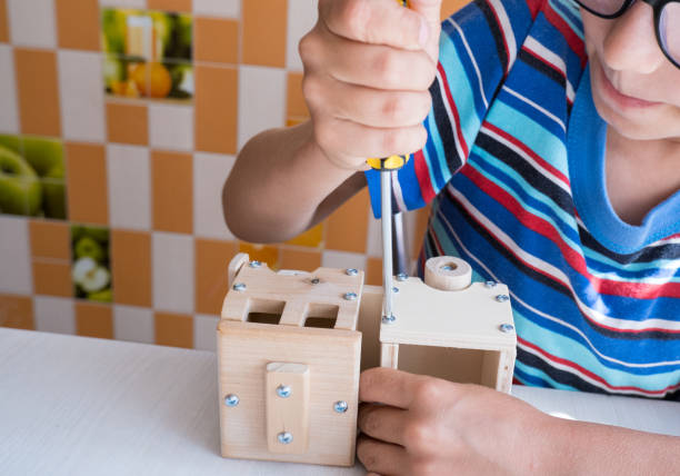 istock An 8-year-old boy assembles a wooden constructor by himself with a screwdriver. Close-up hands 1618024956