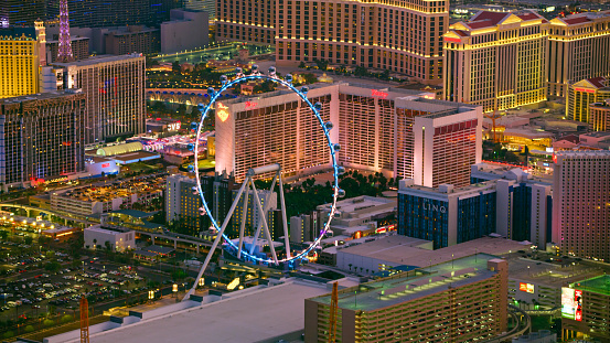 Las Vegas, Nevada/ USA - March 14, 2022: Aerial view of High Roller observation wheel in Las Vegas on The Strip at night.\n\nLas Vegas is the largest city in the US state of Nevada and a world-renowned center for gambling, shopping, fine dining and entertainment. It is mainly famous for its many casinos and the accompanying entertainment-tourism activities, which earned it the nickname of the Entertainment Capital of the World.