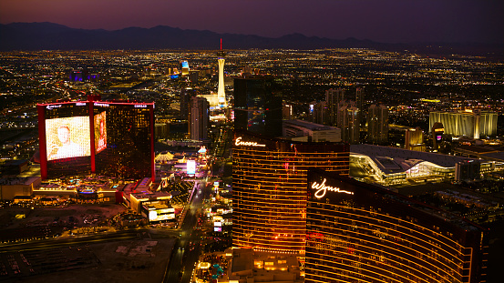 Las Vegas, Nevada/ USA - March 14, 2022: Aerial view of hotels, lights and neon signs of the Las Vegas Strip at night.\n\nLas Vegas is the largest city in the US state of Nevada and a world-renowned center for gambling, shopping, fine dining and entertainment. It is mainly famous for its many casinos and the accompanying entertainment-tourism activities, which earned it the nickname of the Entertainment Capital of the World.