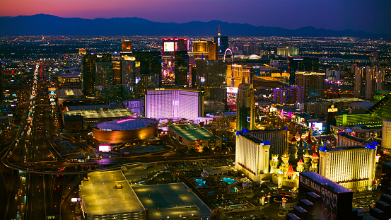 Las Vegas, Nevada/ USA - March 14, 2022: Aerial view of lights of Las Vegas and the highway running along The Strip at night.\n\nLas Vegas is the largest city in the US state of Nevada and a world-renowned center for gambling, shopping, fine dining and entertainment. It is mainly famous for its many casinos and the accompanying entertainment-tourism activities, which earned it the nickname of the Entertainment Capital of the World.