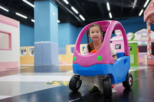 little girl driving a toy car