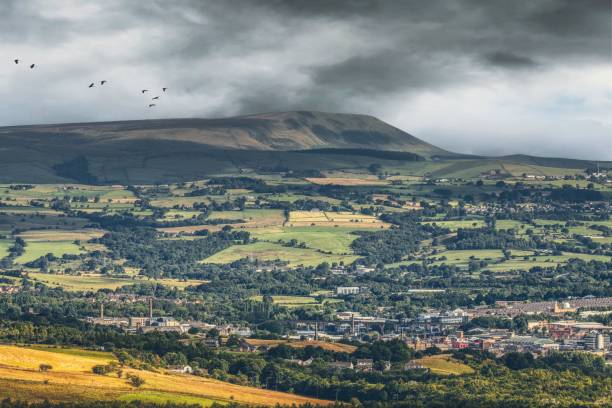 scenic view of green pendle hill with the town of burnley, lancashire in the foreground - pendle imagens e fotografias de stock