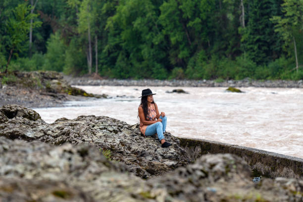 Wet'suwet'en First Nations Woman, Canada Canadian indigenous first nations Wet'suwet'en woman watching people fish salmon in Bulkley River, Witset Canyon, British Columbia, Canada. prince george photos stock pictures, royalty-free photos & images