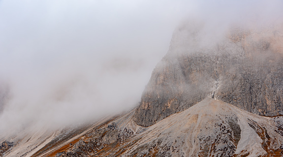 Foggy rocky mountain landscape at sunrise with blue sky. of the Dolomites at Passo Sella South Tyrol in Italy.