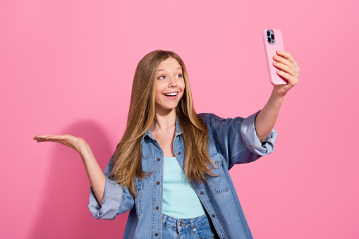 Portrait of charming funny girl hold phone empty space advertise modern device shop chatting live stream isolated on pink color background.