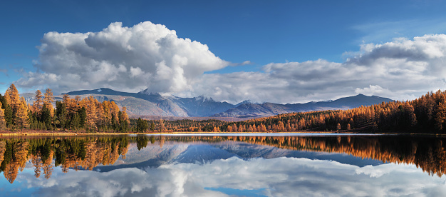 Picturesque lake in the mountains of Altai, autumn day, sky reflection in the water
