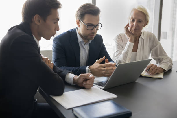 istock Serious younger and older coworkers watching online project 1618133283