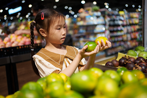 Children choosing oranges in supermarket