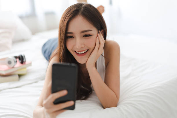istock Happy woman relaxing using and talking by smartphone on the bed at home.technology and communication concept 1618162269