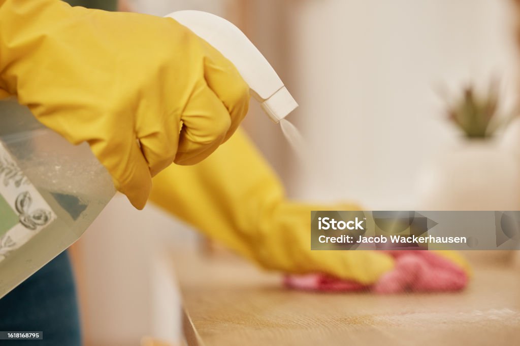 Hand, spray and a woman cleaning a wooden surface in her home for hygiene or disinfection. Rubber gloves, product and bacteria with a female cleaner using detergent to spring clean in an apartment Housekeeping Staff Stock Photo
