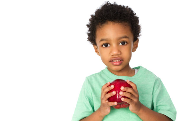 young boy retención de manzana - apple healthy eating eating black fotografías e imágenes de stock