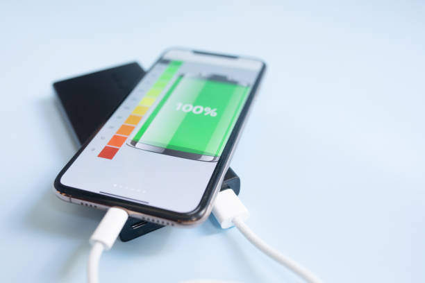 istock A smartphone charging with black powerbank on blue background. 1618232631