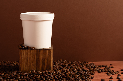 White coffee cup laying on the coffee beans, logo space concept