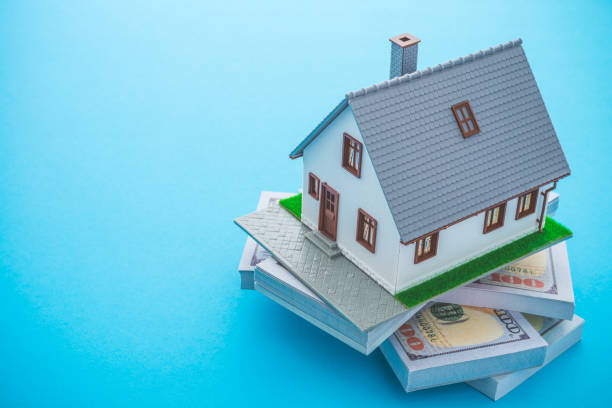 istock House model, bill dollar banknotes on blue background with copy space. 1618235314