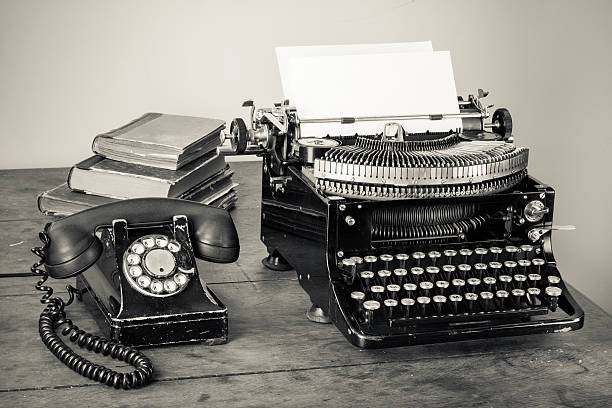 vintage, telefone, máquina de escrever, livros antigos na mesa desaturated foto - typewriter retro revival old obsolete - fotografias e filmes do acervo