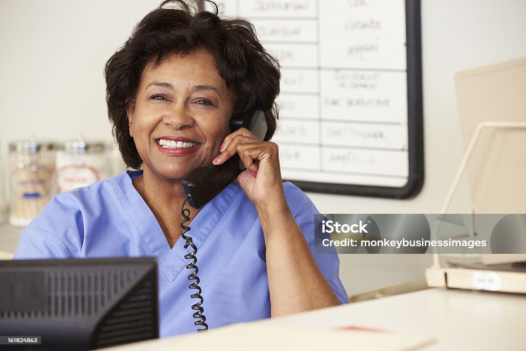 Nurse Making Phone Call At Nurses Station Nurse Making Phone Call At Nurses Station Smiling To Camera Nurse Stock Photo
