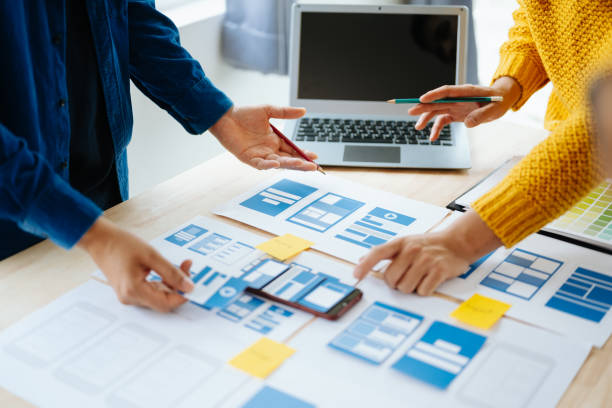 istock Close up view of UI developer team brainstorming on their project with laptop, smartphone and digital tablet. Creative digital development agency. in office 1618259935