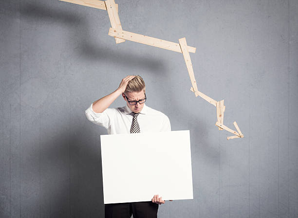 istock Frustrated businessman holding panel in front of graph pointing 161826764
