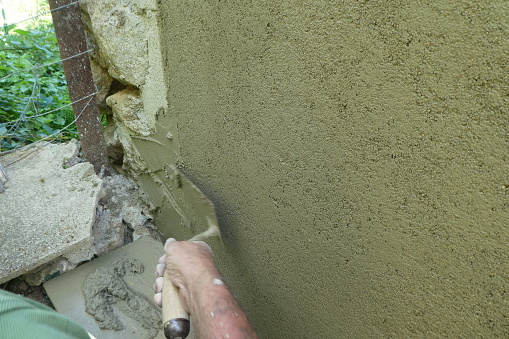 finishing a wall by smoothing cement with a trowel in summer