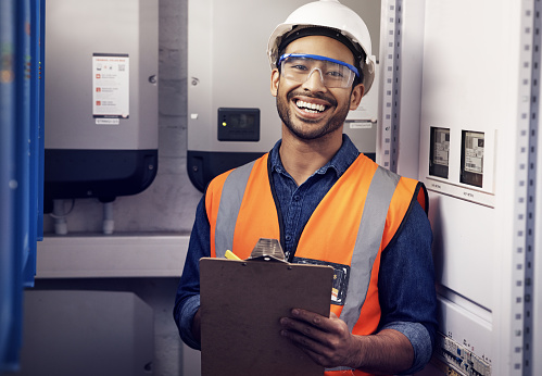 Portrait of happy man, engineering and technician at control panel, inspection and maintenance planning on clipboard. Male electrician smile at electrical substation for power, system and checklist