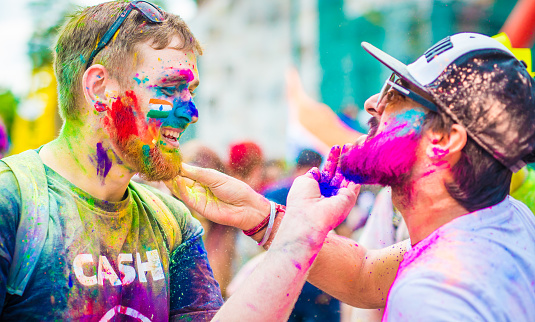 Khakiv, Ukraine - 19 May 2018: People sprinkle colorful paints during the festival. People with colorful faces celebrating holi fest