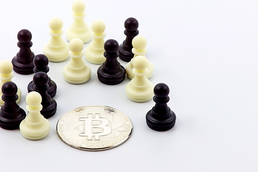 Santander, Cantabria, Spain; 08, 15, 2023: Chess pawns surrounding a bitcoin coin. Herd concept, strategy, cryptocurrencies