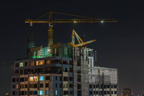 istock Crane in high building construction site with lighting at night. 1618289666