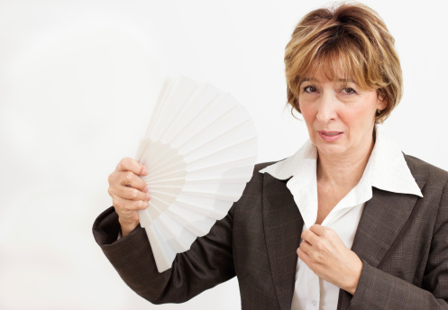 Mature businesswoman  cooling herself with a fan.